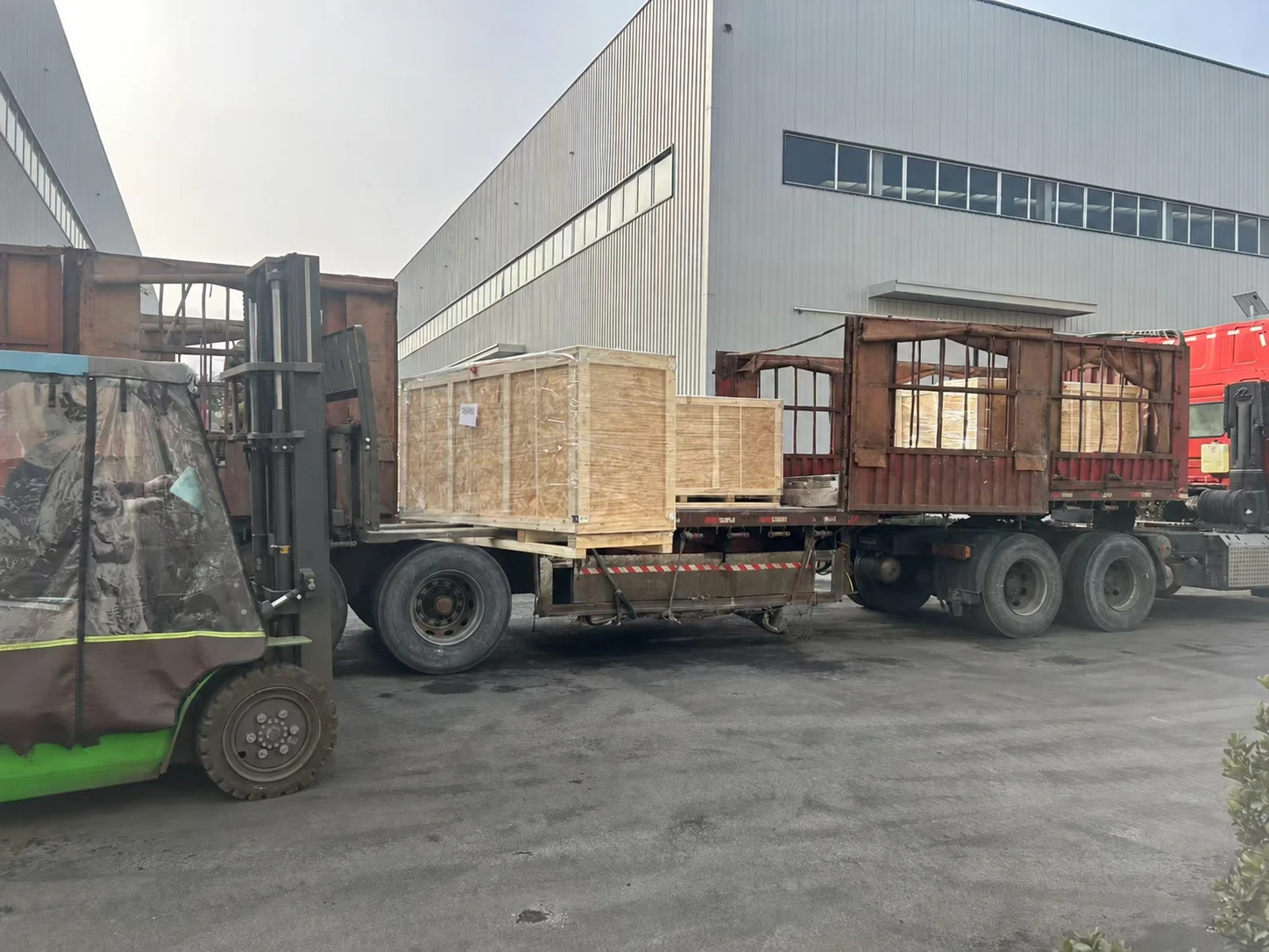 Wooden crates being loaded onto a truck outside factory buildings
