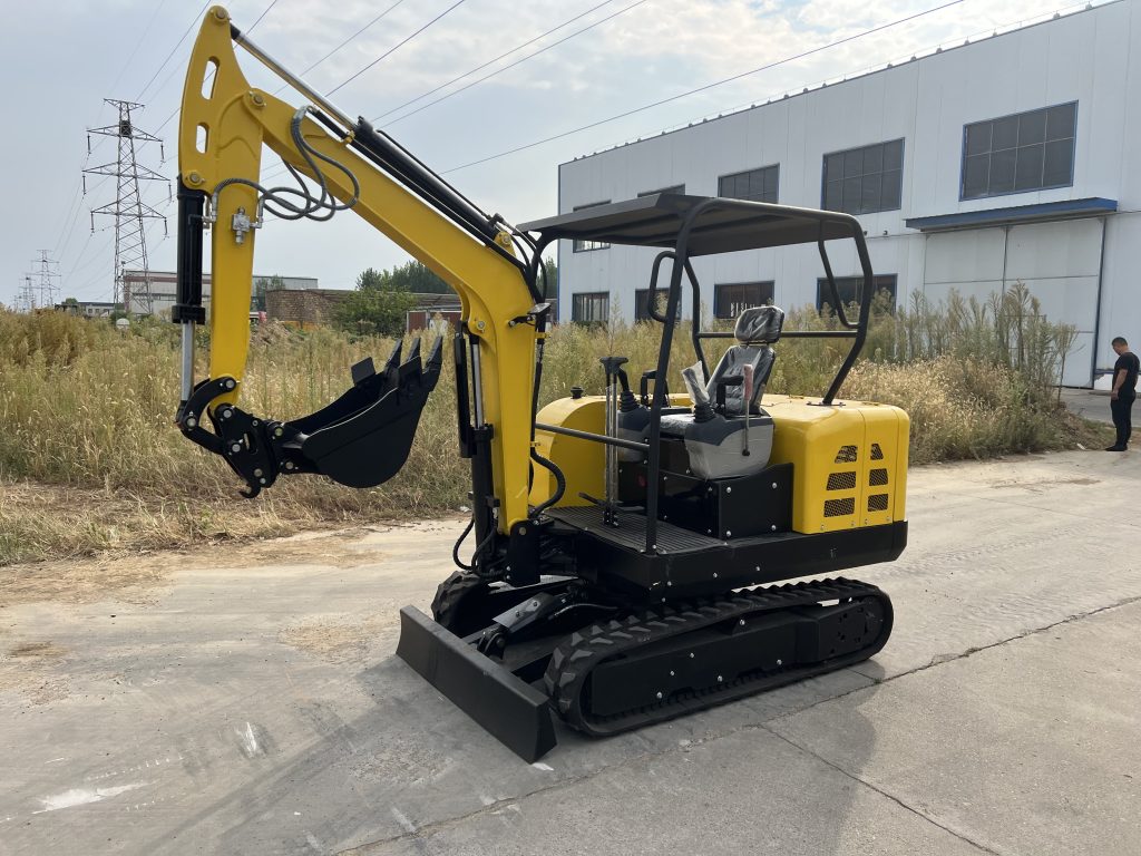 Yellow compact excavator with an open canopy and bucket outside a factory building