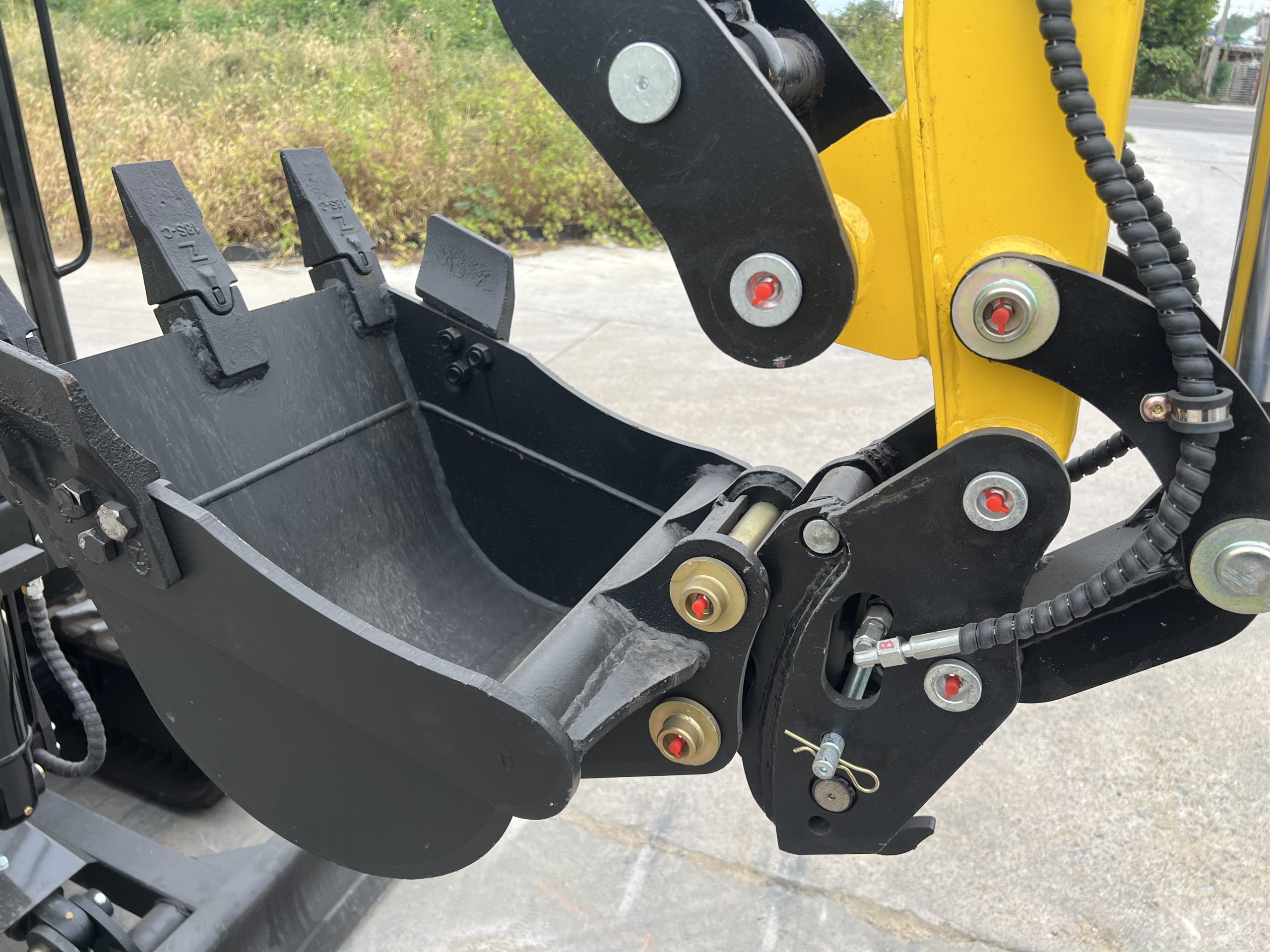 Bucket mounting pins, linkage and hydraulic hose connection on a yellow mini excavator