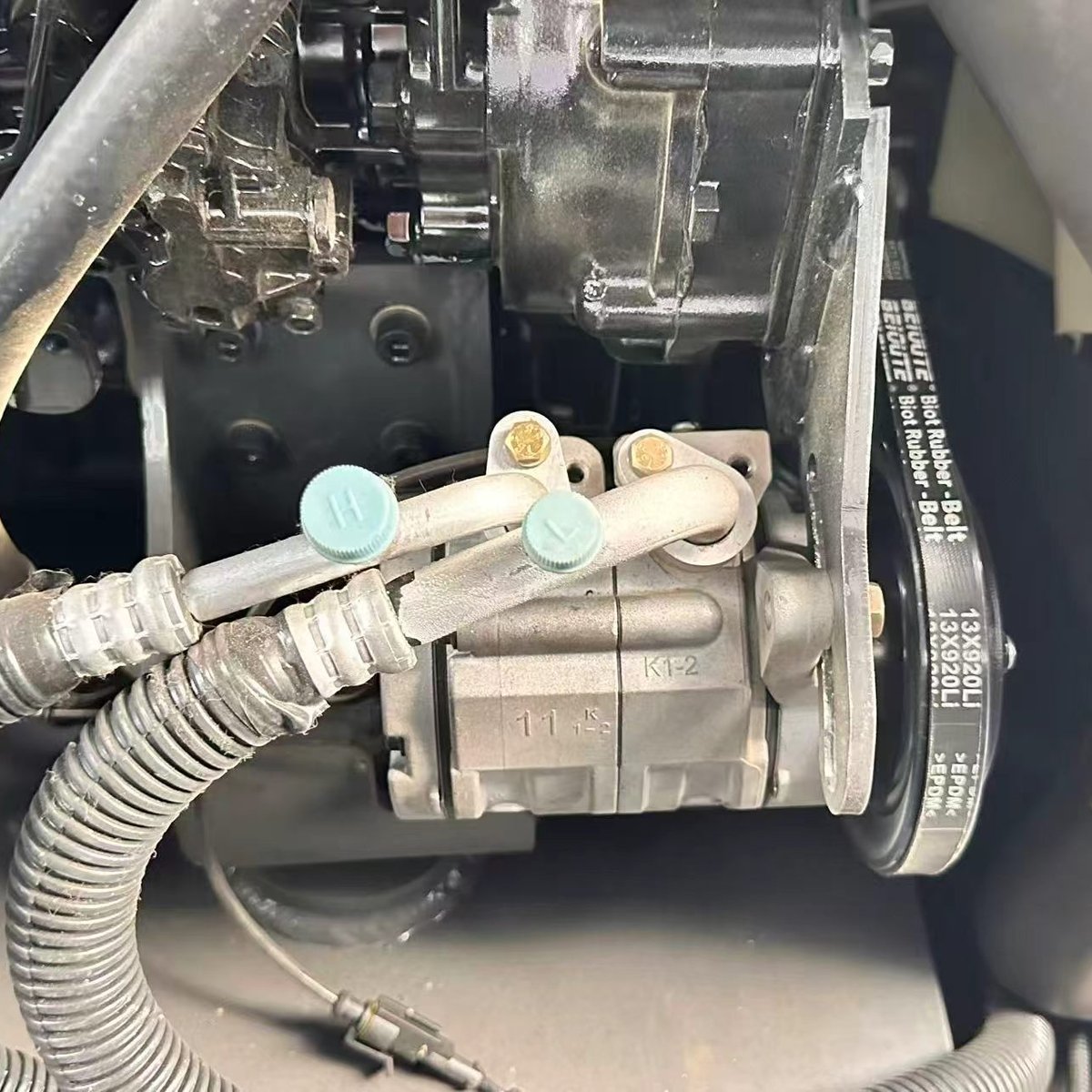 Hydraulic pump and belt drive assembly on a mini excavator engine