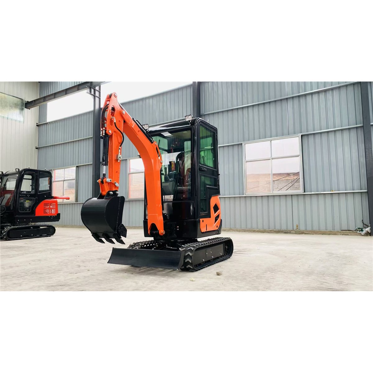 Orange HL18 mini excavator with enclosed cab and rubber tracks in a workshop