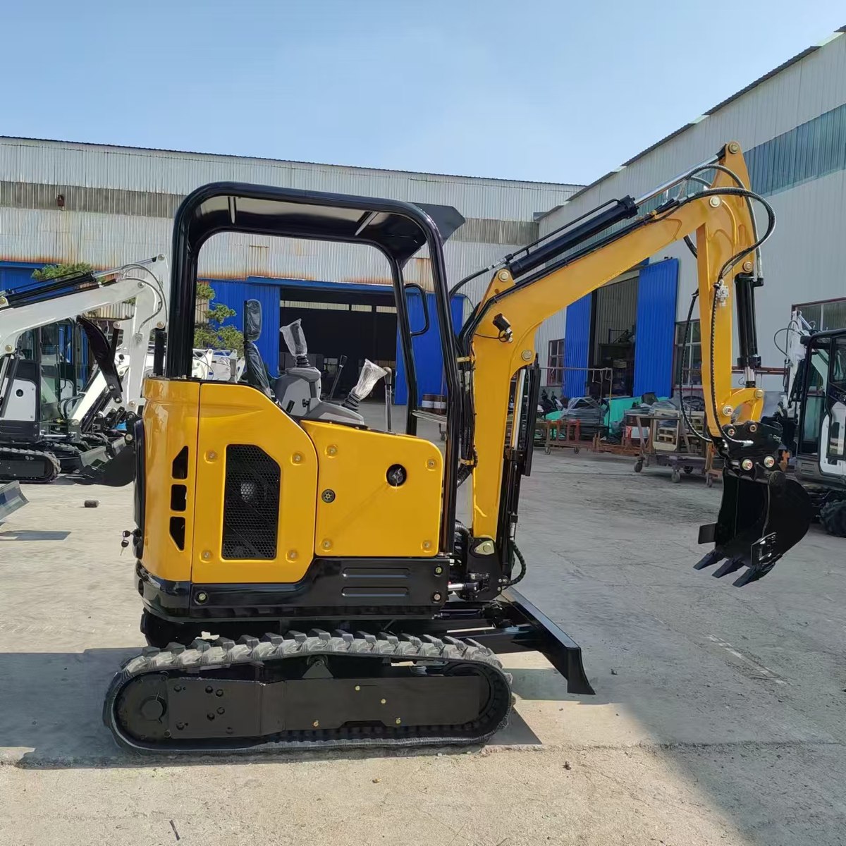 Yellow HL22 excavator with an open canopy and rubber tracks photographed outside a workshop