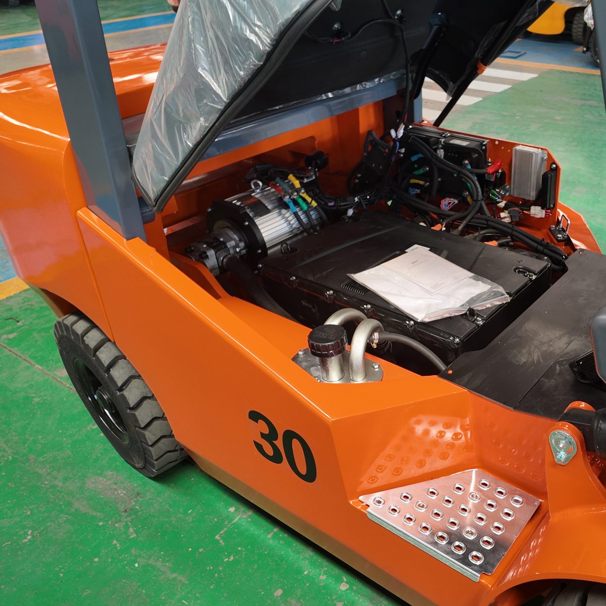 Open service compartment of an orange 30-marked forklift in a factory
