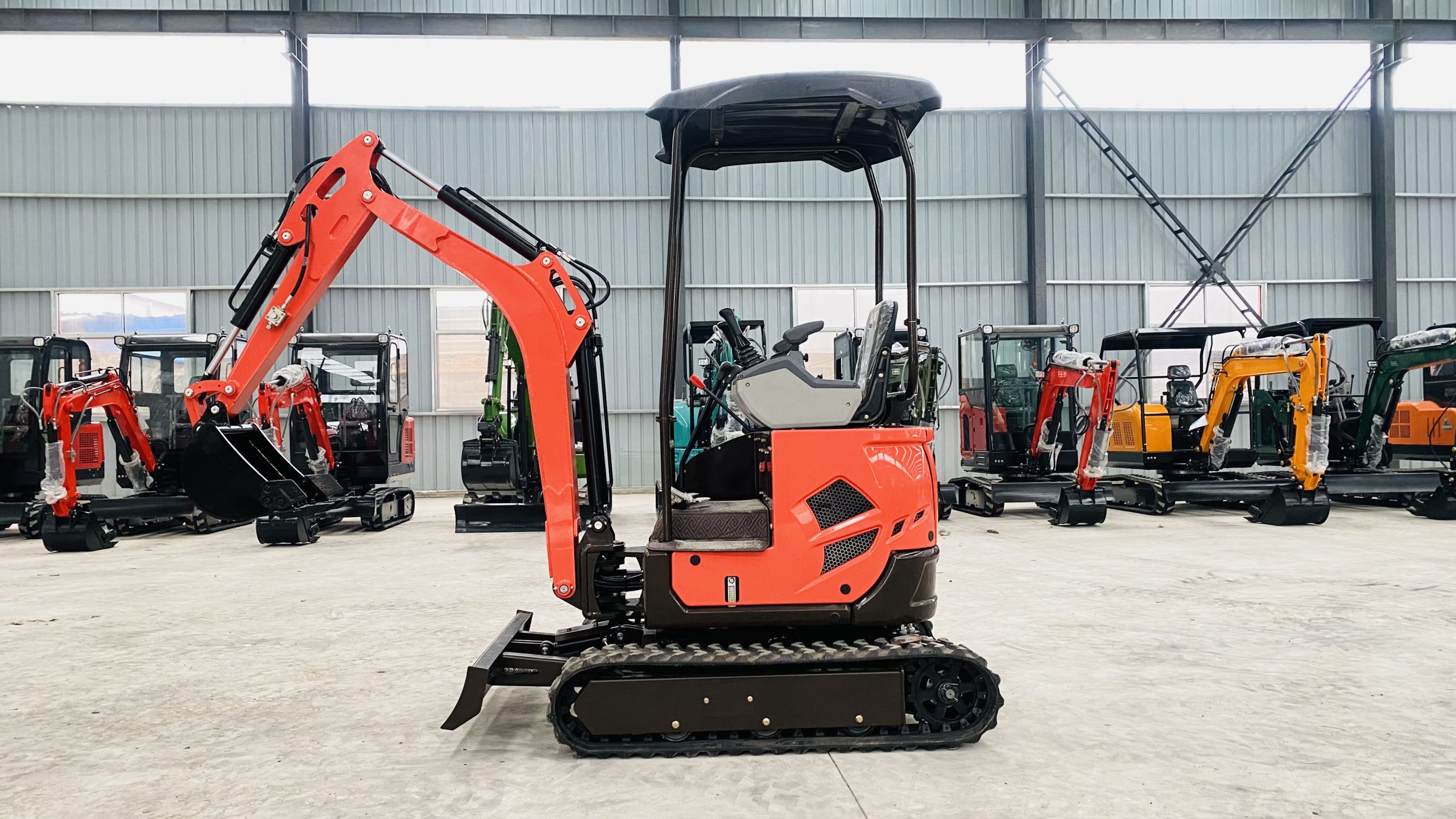 Orange canopy mini excavator with bucket and tracks photographed inside a workshop